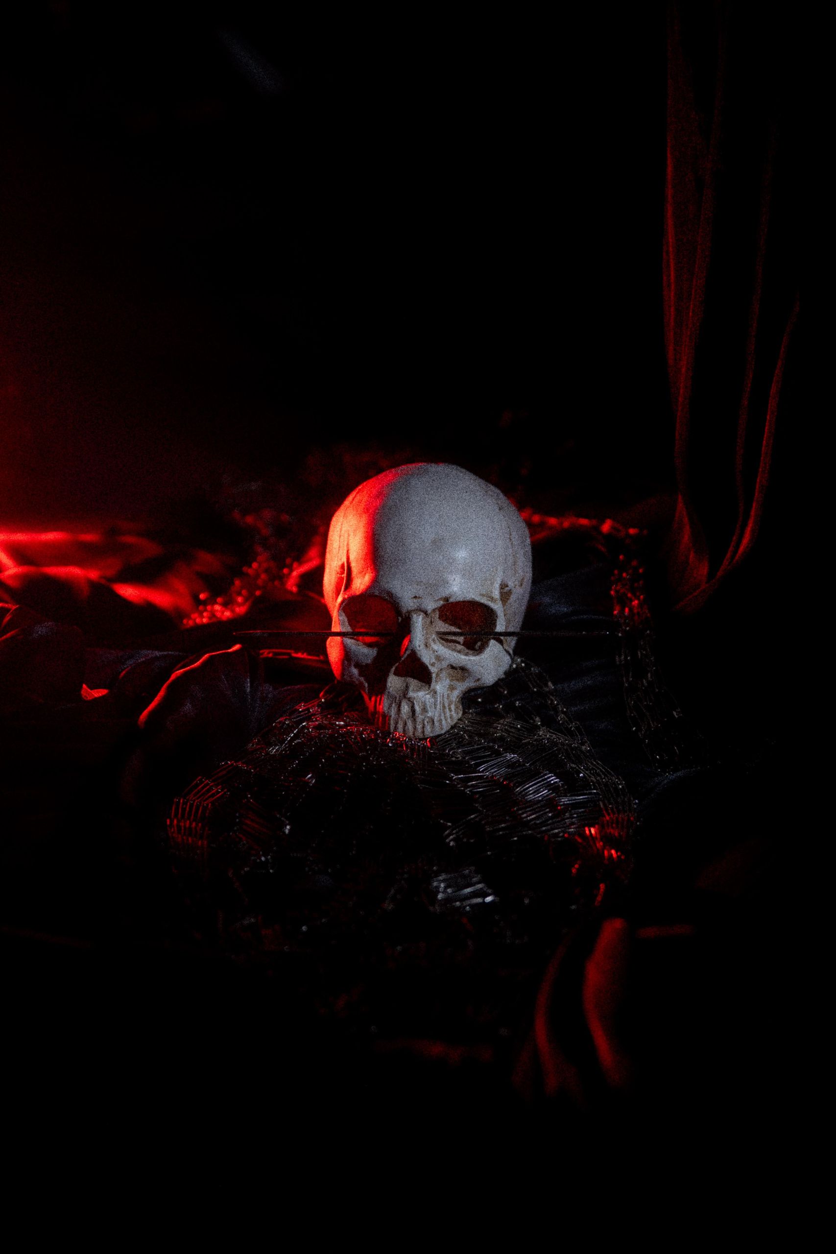 A model-skull lying on fabric with red light shining on it creating a dark atmosphere